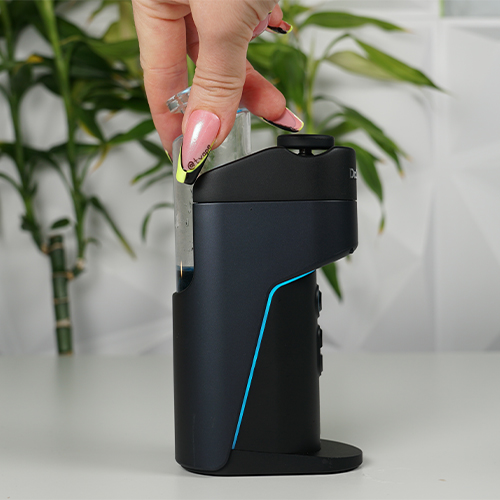 Dr. Dabber Switch Go sobre una mesa mientras una mujer conecta su bubbler de vidrio