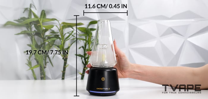 Una mano sostiene la vapor cup Tronian Omegatron 2, con las medidas marcadas: 19,7 cm (7,75 pulgadas) de alto y 11,6 cm de ancho.